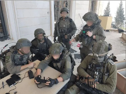 צוות שלם מצטופף סביב מסך השלט של מטיס יחיד כדי לראות את שידור הרחפן  